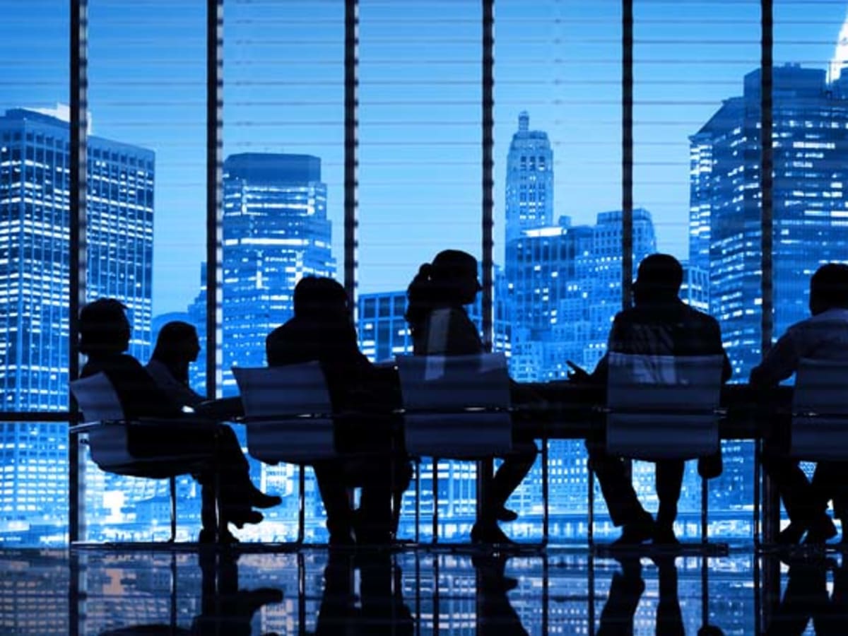An investment committee in session at a boardroom table against a city skyline